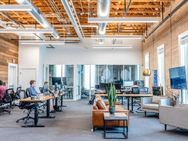 Modern office space with wooden ceiling, desks, and chairs.